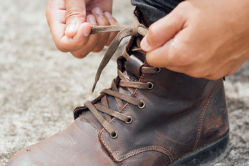 Men tying shoes, Men fashion brown leather boots. Toned picture.
