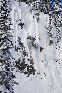 A male freeskier drops a huge cliff at Revelstoke Mtn Resort, BC