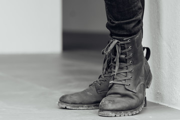 Close up view on man's legs in black jeans and brown leather boots. black and white