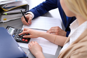 Bookkeeper or financial inspector and secretary making report, calculating or checking balance. Internal Revenue Service inspector checking financial document. Audit concept.