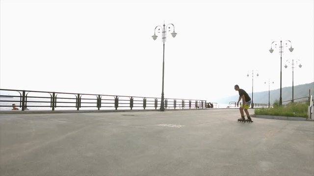 Young sporty man learns to roller skate on waterfront HD