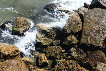 The waves of the sea beating against the sharp rocks and stones coast