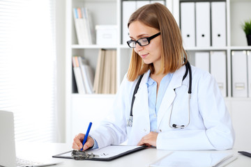 Female doctor  writing a medical prescription at clipboard