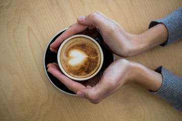 Woman holding cup of coffee on table