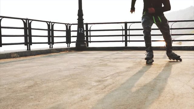 Mans legs roller skating inline close up on the asphalt sunset HD