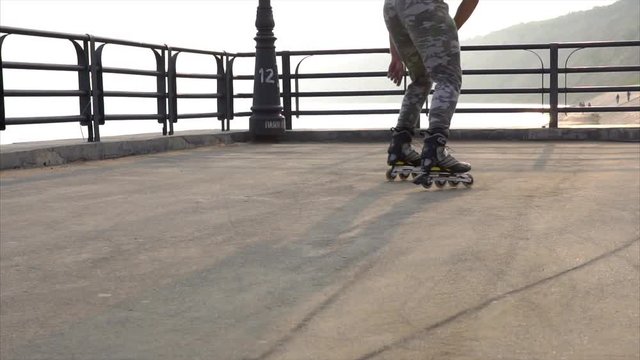 Mans legs roller skating inline close up on the asphalt sunset HD