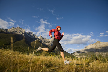 A young woman trail running in Canmore, AB
