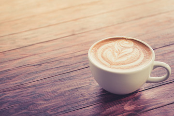 a cup of cappuccino coffee on dark brown wood in morning light