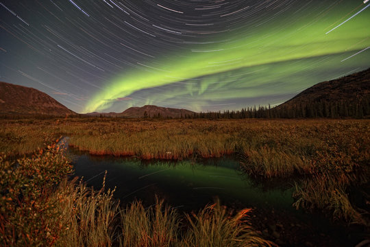 Timed exposure of startrails and aurora over unnamed stream near Whitehorse, Yukon.