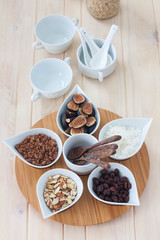 Breakfast bar with healthful choices like nuts, grains, fruit. Light wood table. 