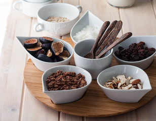 Breakfast bar with healthful choices like nuts, grains, fruit. Light wood table. 