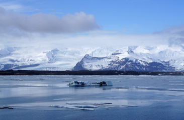 Fototapeta na wymiar ice sheet on the water with snow mountain background