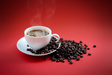 Coffee beans and red coffee cup on red background