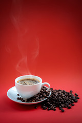 Coffee beans and red coffee cup on red background