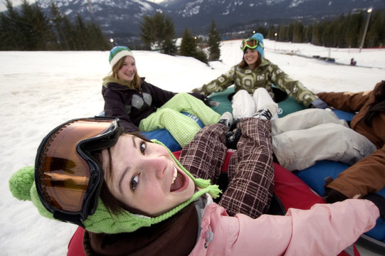 Girls laugh while playing on a giant tube at Whistler Blackcomb Tube Park, Whistler, BC Canada