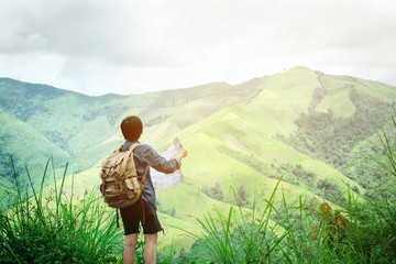 hipster traveler man holding map at mountains with amazing view