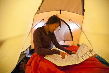 A young woman wakes up  and plans the day while camping in Jasper Provincial Park, Alberta, Canada