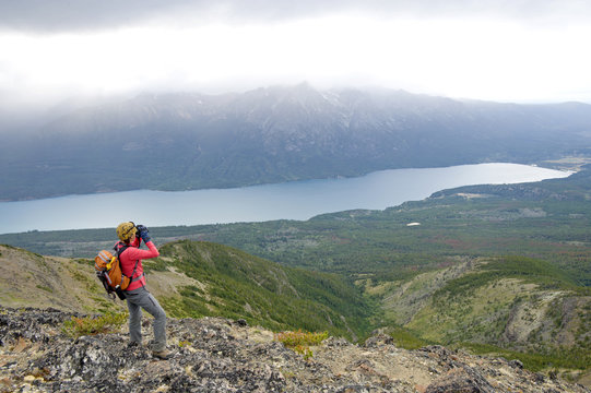 A woman surveys over Tatlayoko Lake with binoculars, British Columbia Coast Mountains
