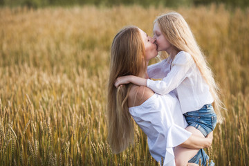 Fototapeta na wymiar beautiful young mother and her daughter at the wheat field