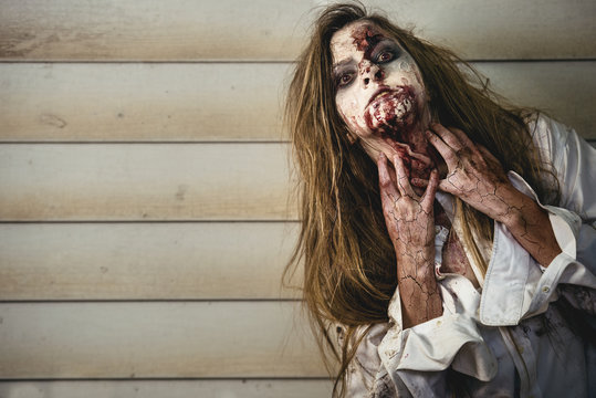 Scary and bloody zombie woman at the backyard. Halloween concept