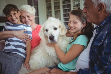 Grandparents and grandchildren sitting on sofa with pet dog