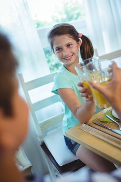 Smiling girl toasting glass of orange juice