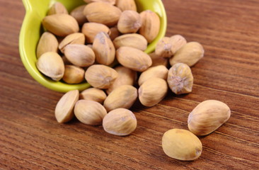 Obraz premium Pistachio nuts in bowl on wooden table, healthy eating