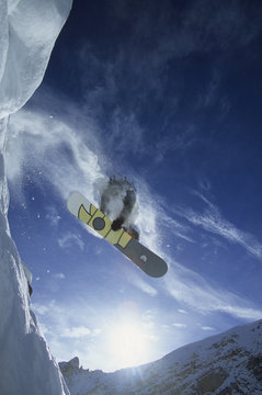 Low angle view of a snowboarder catching some air in the backcountry, Golden, British Columbia, Canada