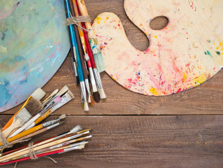 Paints, brushes and palette on the wood background. The workplace of the artist. Banner for school
