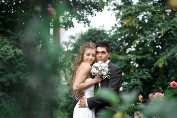 Brunette groom hugs radiant bride tender while they stand among