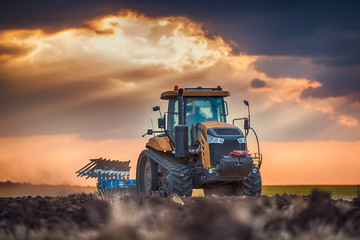 Farmer in tractor preparing land with cultivator - obrazy, fototapety, plakaty