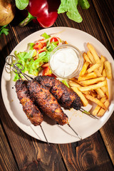 Grilled shish kebab served with fried chips and salad