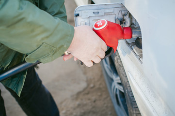 man at a gas station fills the fuel in the vehicle tank. adult man with a mustache and glasses, fueling car before a long journey on the road to non-network gas station