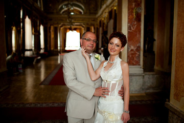 Fototapeta premium Short-haired bride strokes groom's chin while they pose in old r