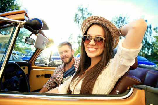 Happy to travel together. Joyful young couple smiling while riding in onvertible