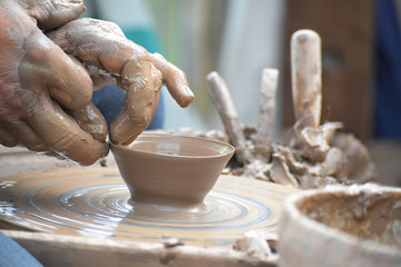 potter's hands creating a ceramic of clay on the wheel in the pottery