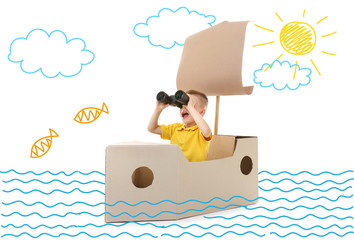 Fototapeta premium Little boy playing with cardboard ship. Drawing on background.