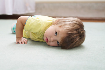 Obraz na płótnie Canvas Little Caucasian girl lying on the carpet
