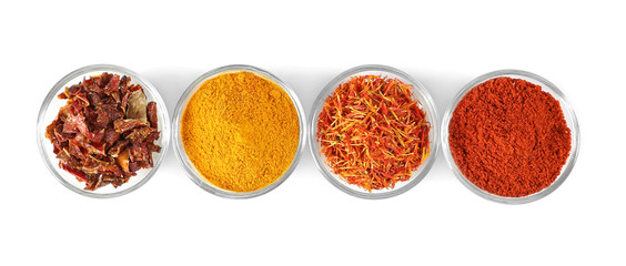 Glass bowls with various spices in a row on white background