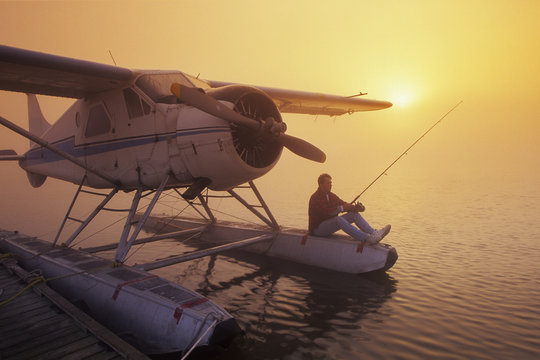 man fishing from float plane, along Red River, Manitoba, Canada