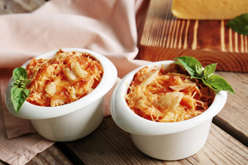 Tasty pasta Al Forno in ceramic bowls on wooden table