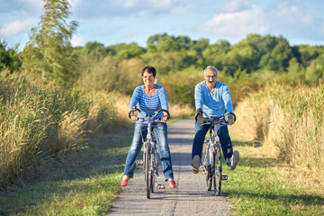 zwei Senioren haben Spaß beim Radfahren in der Natur - obrazy, fototapety, plakaty