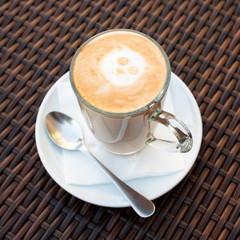 Cup of hot latte art coffee on wicker wooden table.