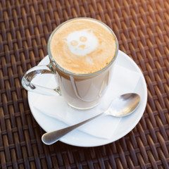 Cup of hot latte art coffee on wicker wooden table.