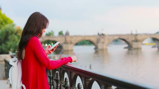 Young caucasian woman using her smartphone outdoor background famous bridge.