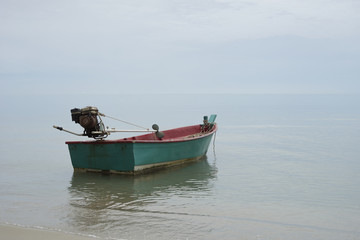 Naklejka premium Traditional wooden fishing boat floating on the peace surface wave of the seas,in the afternoon against the blue waters,selective focus,minimalism