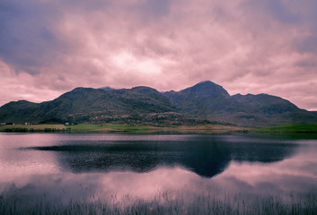 Fototapeta premium Fjord at sunset. Mountain Reflection. Rocky beach in evening, Norway
