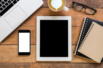 Office stuff with blank screen smartphone, blank screen tablet, laptop,  leather notebook, glasses and cup of coffee. Top view with copy space.Office desk table concept.