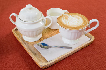A cup of coffee with sugar, spoon and water on wooden background