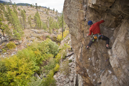 A man traditional rockclimbing the route Malpractice 10d, Skaha, BC